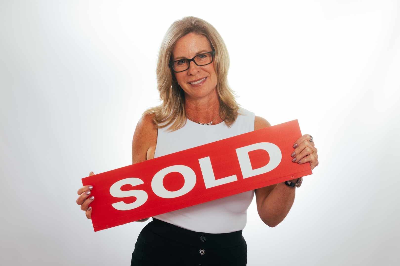 Tracey Dixon studio headshot holding a SOLD sign — The Dixon Team